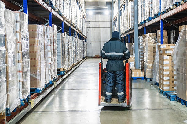warehouse worker operating pallet jack in cold storage warehouse